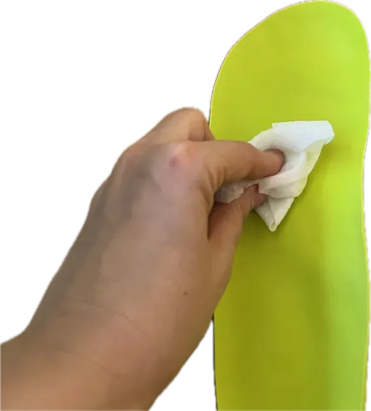 Mano limpiando plantilla ortopédica con paño húmedo