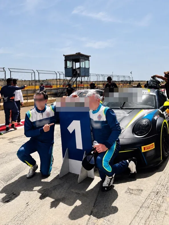 Piloto de automovilismo en el circuito tras la carrera, con los rostros y la identificación del coche ocultos