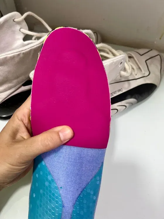 Plantilla Motorsport personalizada sostenida junto a la bota de competición