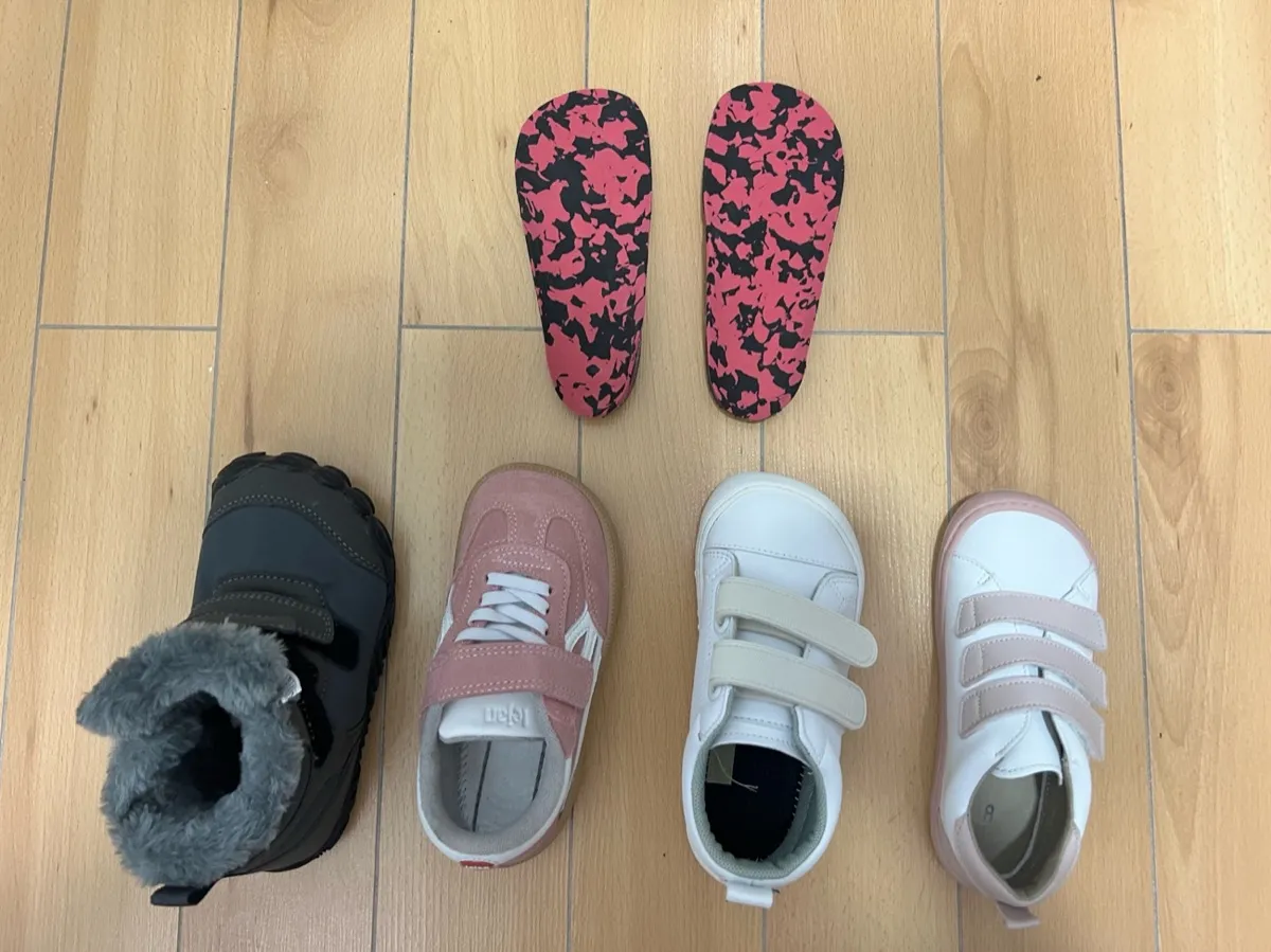 Soportes plantares personalizados junto a cuatro pares de zapatos infantiles revisados en Centro Podológico Henao para tratamiento ortopodológico